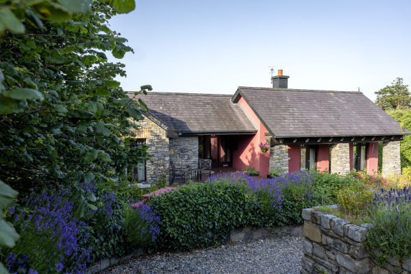 The stone and slate lodge with lavender planting in the garden