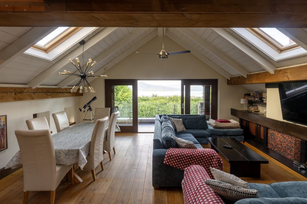 Open-plan dining and living area with a vaulted ceiling and patio doors to the garden