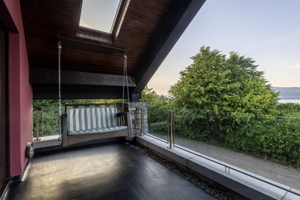 Covered veranda with a glass balustrade and a swing seat