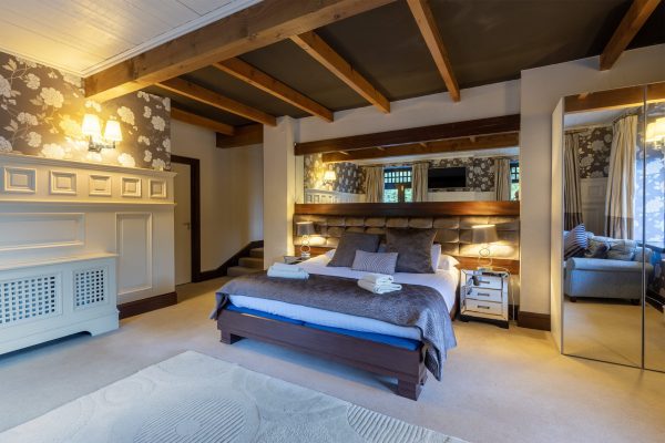 Double bedroom under exposed beams with mirrored wardrobes